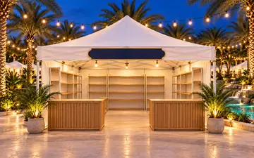 a white walk-in market tent with wooden counters under string lights at twilight