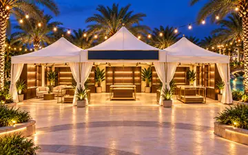 a three-canopy white market pavilion with displays and seating under string lights at twilight